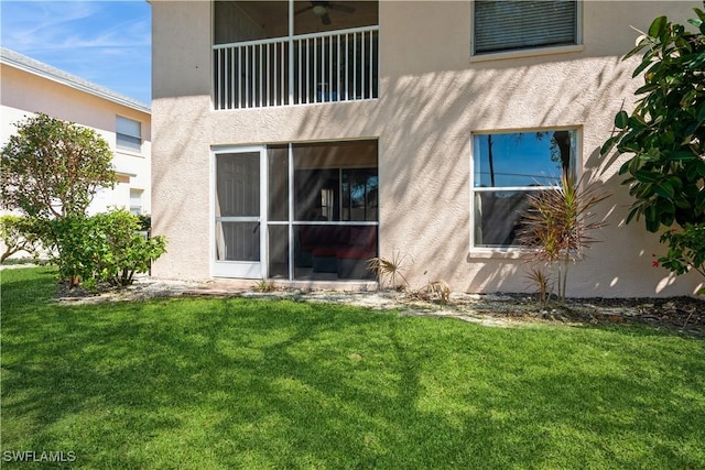 rear view of house featuring stucco siding and a yard