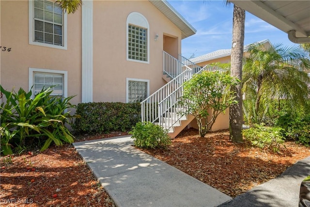 exterior space with stairway and stucco siding