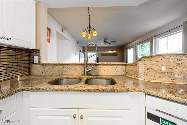 kitchen with plenty of natural light, light stone countertops, backsplash, and a sink