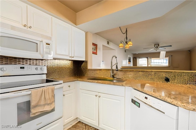 kitchen with a sink, light stone counters, tasteful backsplash, white cabinetry, and white appliances