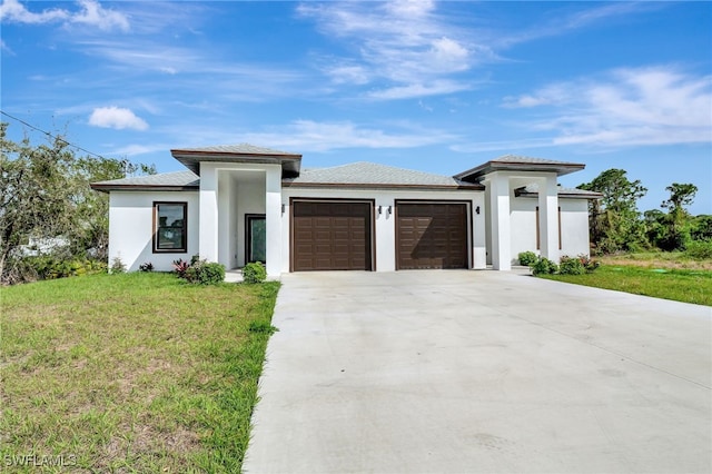 prairie-style house featuring a garage, stucco siding, concrete driveway, and a front yard