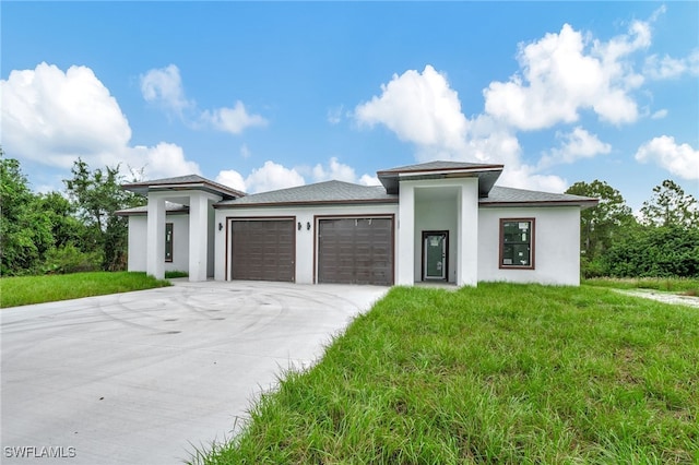 prairie-style home featuring concrete driveway, an attached garage, and stucco siding