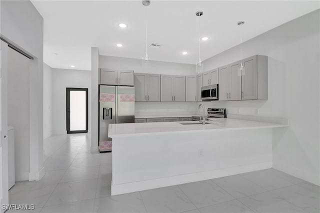 kitchen with a peninsula, light countertops, stainless steel appliances, gray cabinetry, and a sink