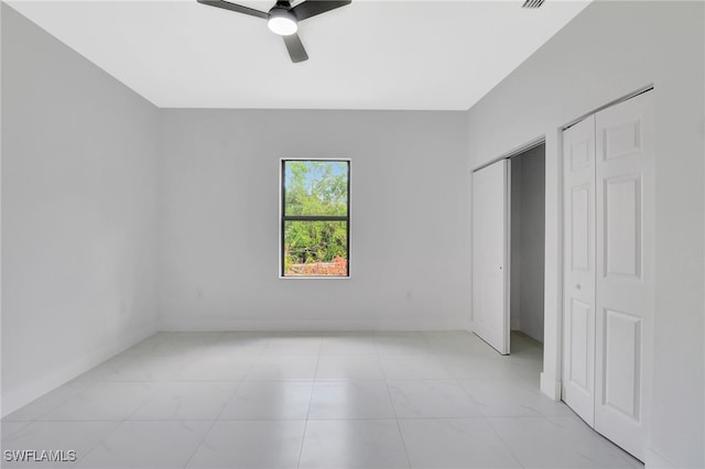 unfurnished bedroom with two closets, a ceiling fan, and baseboards