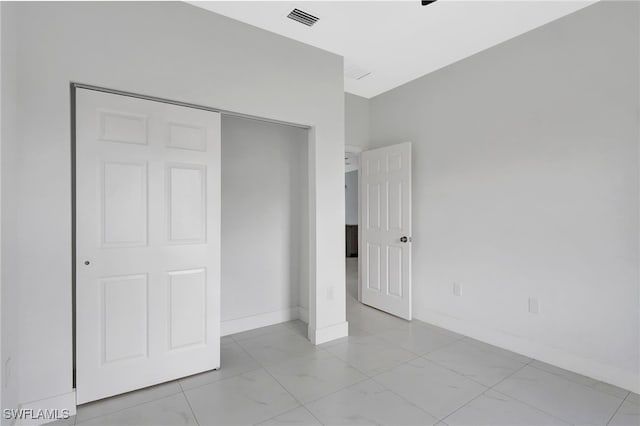 unfurnished bedroom featuring marble finish floor, baseboards, visible vents, and a closet