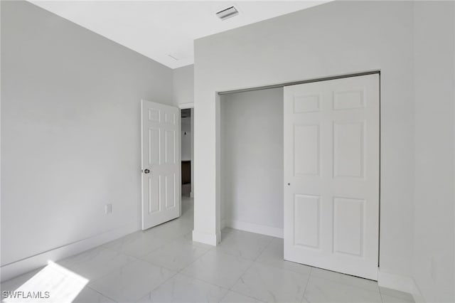 unfurnished bedroom featuring a closet, marble finish floor, visible vents, and baseboards