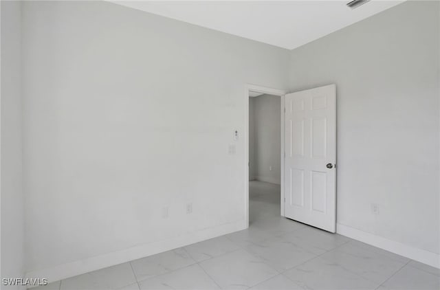 unfurnished room with marble finish floor and baseboards