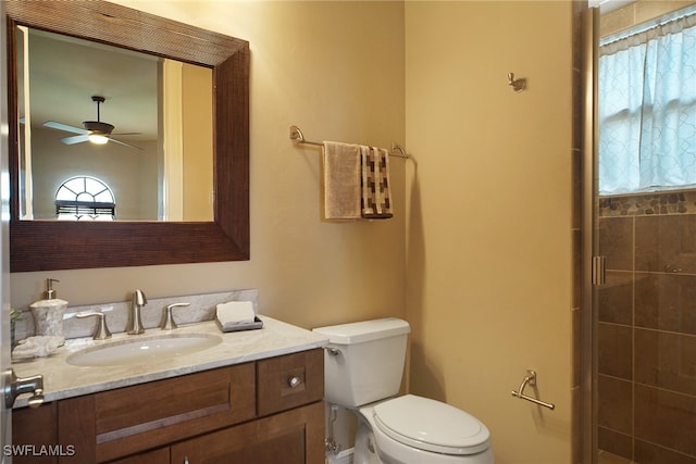 full bathroom featuring toilet, ceiling fan, tiled shower, and vanity