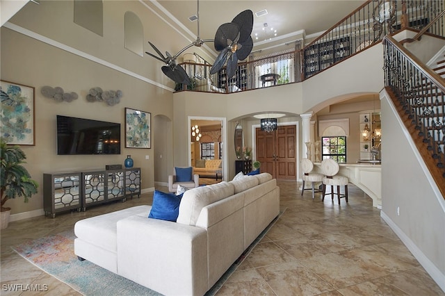 living room with arched walkways, decorative columns, visible vents, baseboards, and ceiling fan with notable chandelier