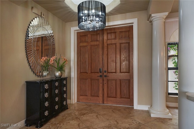 foyer featuring baseboards, an inviting chandelier, and ornate columns