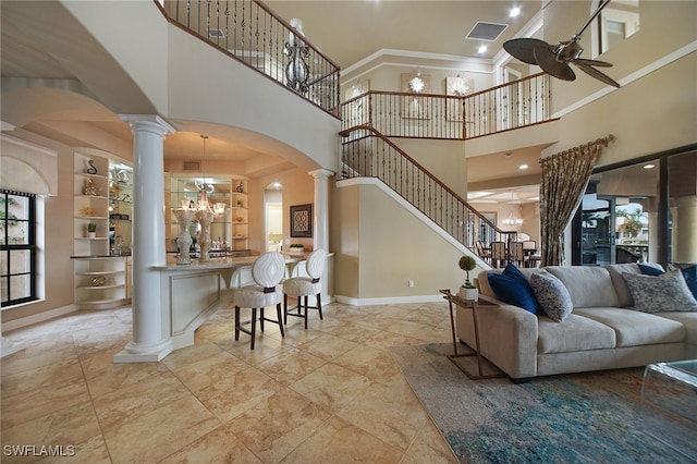 living room featuring arched walkways, ornate columns, visible vents, baseboards, and ceiling fan with notable chandelier