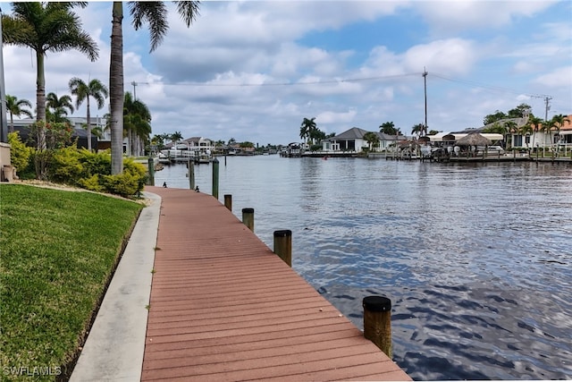 dock area featuring a water view, a residential view, and a lawn