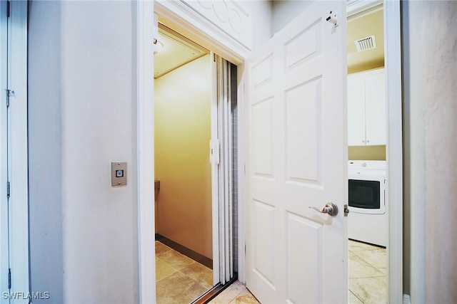 hall featuring washer / dryer, visible vents, and light tile patterned floors