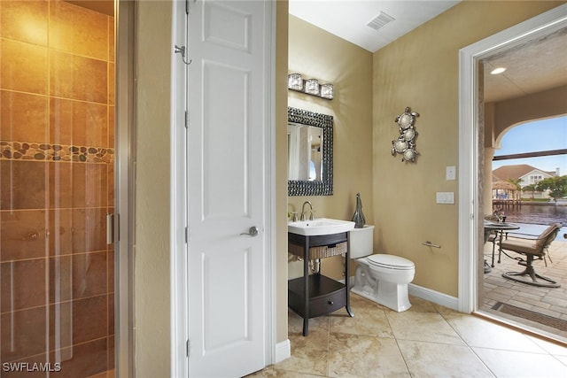 bathroom featuring tile patterned flooring, toilet, a sink, visible vents, and baseboards