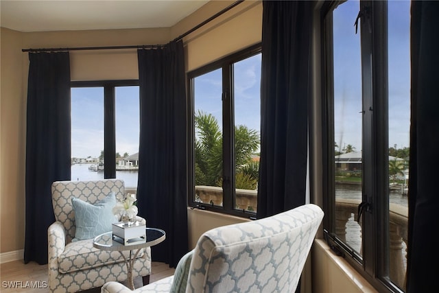 interior space featuring light wood-type flooring, a water view, and baseboards