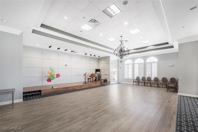 workout room featuring a raised ceiling, baseboards, ornamental molding, and wood finished floors