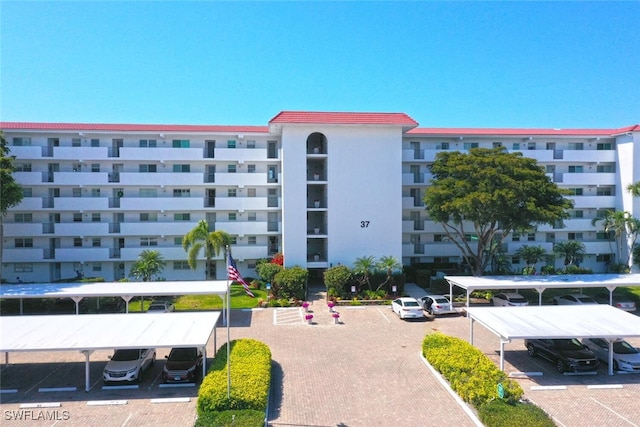 view of building exterior with covered and uncovered parking