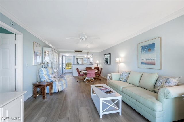 living area with visible vents, wood finished floors, baseboards, ceiling fan with notable chandelier, and ornamental molding