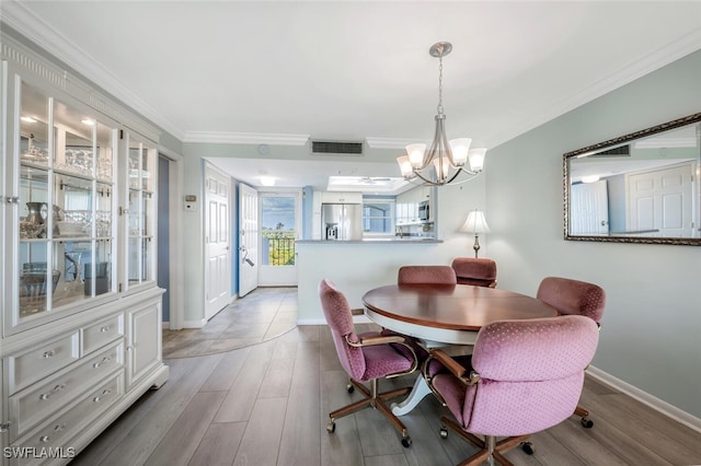 dining space with visible vents, ornamental molding, wood finished floors, baseboards, and a notable chandelier