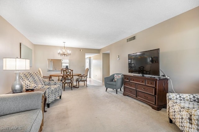 living room with visible vents, light carpet, a textured ceiling, and an inviting chandelier