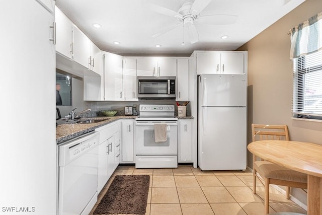 kitchen with white appliances, light tile patterned flooring, a sink, and white cabinets