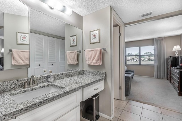 bathroom with visible vents, a textured ceiling, vanity, baseboards, and tile patterned floors