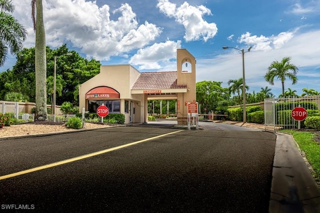 exterior space featuring traffic signs, curbs, a gated entry, and street lights