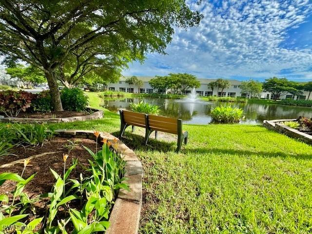 surrounding community with a water view and a lawn