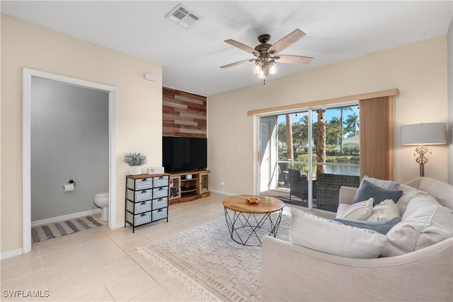 living room with light tile patterned floors, baseboards, visible vents, ceiling fan, and an accent wall