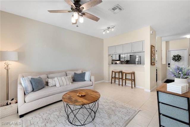 living area with visible vents, baseboards, ceiling fan, and light tile patterned flooring