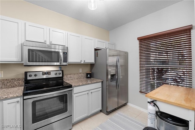 kitchen featuring light tile patterned flooring, appliances with stainless steel finishes, and baseboards