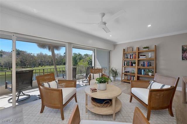 living area featuring light wood-style flooring, a ceiling fan, crown molding, and baseboards