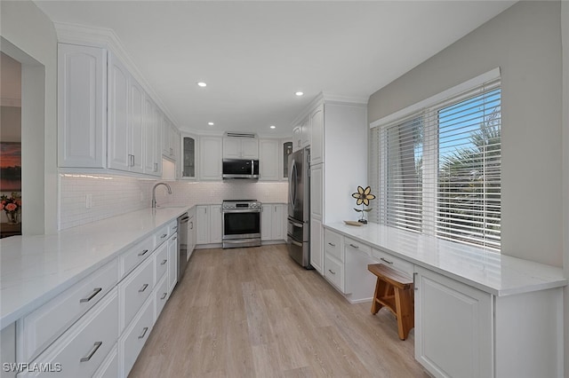 kitchen featuring decorative backsplash, white cabinets, stainless steel appliances, and a sink