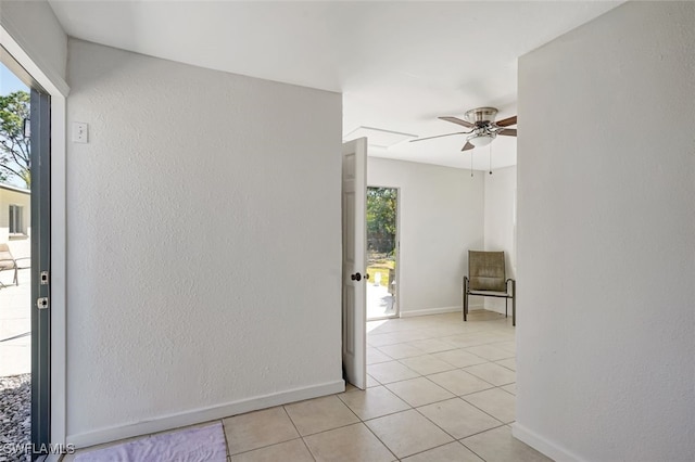 spare room with light tile patterned floors, baseboards, a ceiling fan, and a wealth of natural light