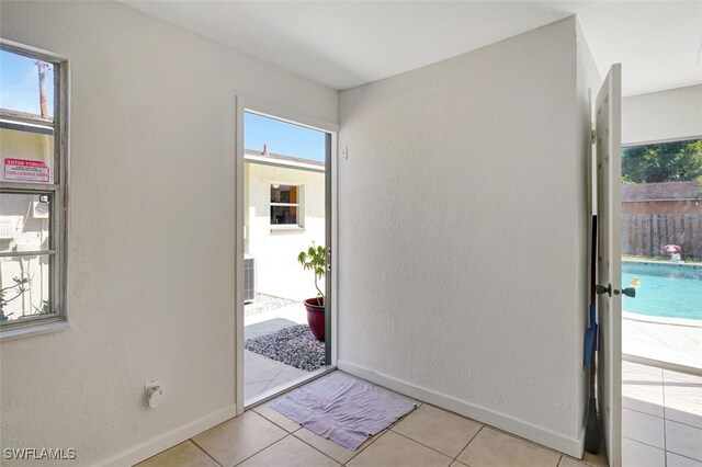 tiled entrance foyer featuring a textured wall and baseboards