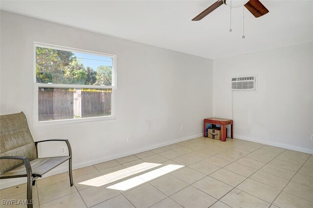 spare room featuring light tile patterned floors, baseboards, a ceiling fan, and a wall mounted air conditioner