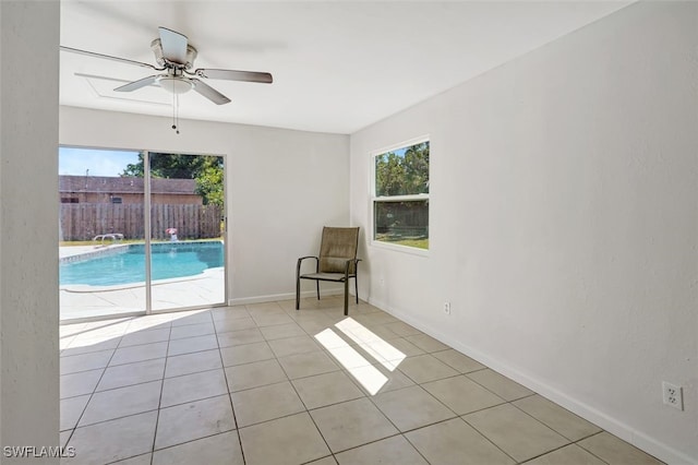 spare room featuring a healthy amount of sunlight, ceiling fan, baseboards, and light tile patterned flooring