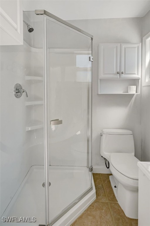 bathroom with a stall shower, tile patterned flooring, and toilet