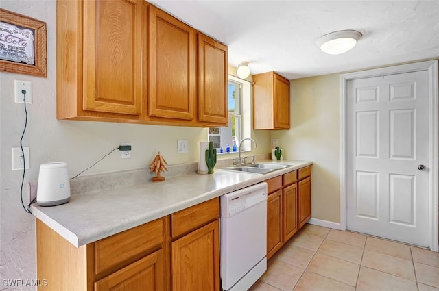 kitchen featuring light tile patterned floors, white dishwasher, a sink, light countertops, and brown cabinetry