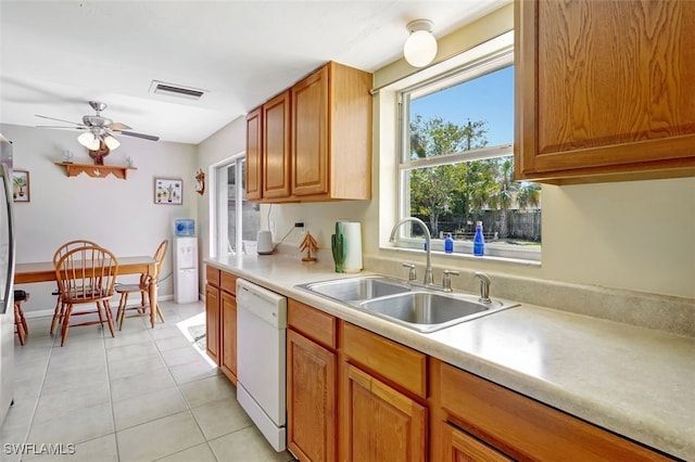 kitchen with light tile patterned flooring, a sink, visible vents, light countertops, and dishwasher