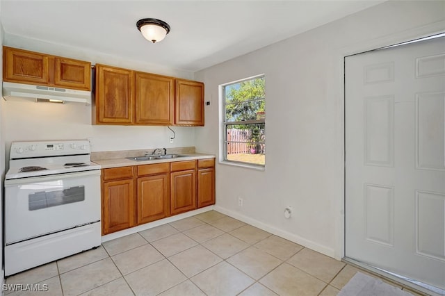 kitchen featuring white electric range oven, brown cabinetry, light countertops, under cabinet range hood, and a sink