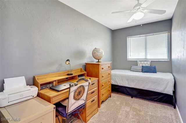 bedroom featuring a textured wall, a ceiling fan, and light colored carpet