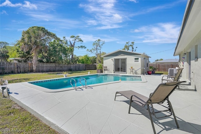 view of pool with a fenced backyard, an outdoor structure, a lawn, a fenced in pool, and a patio area