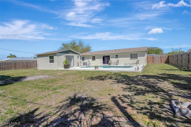 back of property with a fenced in pool, a fenced backyard, a lawn, and stucco siding