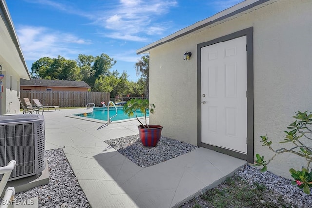 view of swimming pool featuring central air condition unit, a fenced backyard, a fenced in pool, and a patio