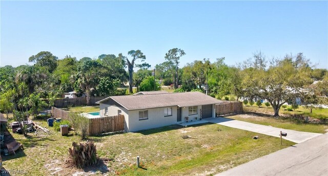 ranch-style house featuring concrete driveway, fence, and a front lawn