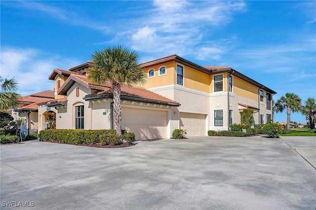 view of front of home with a tiled roof, a garage, driveway, and stucco siding