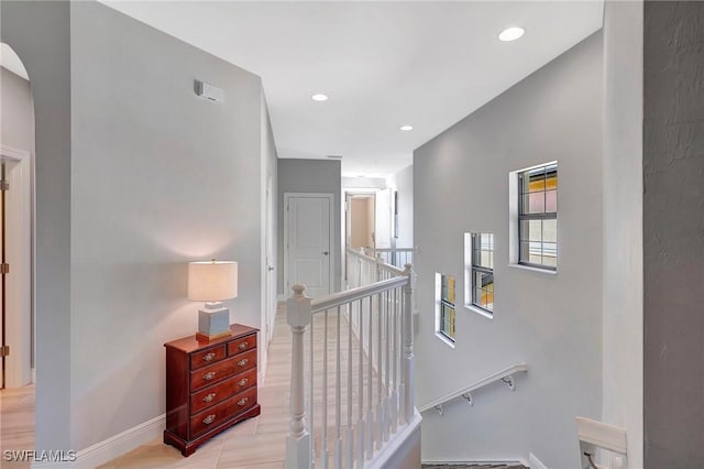 hallway with arched walkways, baseboards, an upstairs landing, and recessed lighting