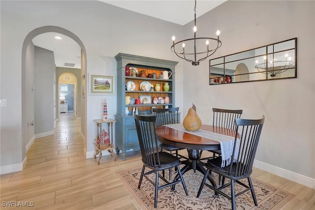 dining space with visible vents, baseboards, arched walkways, a notable chandelier, and wood finish floors