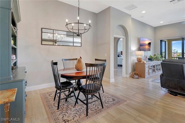 dining area featuring baseboards, light wood-type flooring, arched walkways, and an inviting chandelier